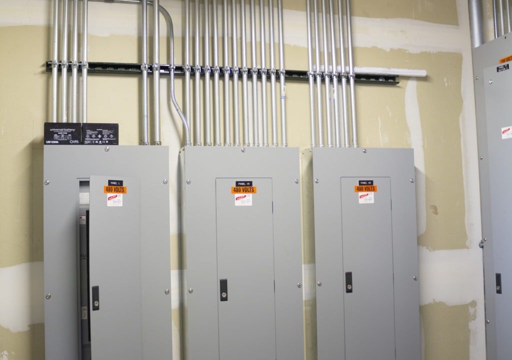 A mobile electrical panel roughed in on a jobsite, conduit and breakers exposed before cover
